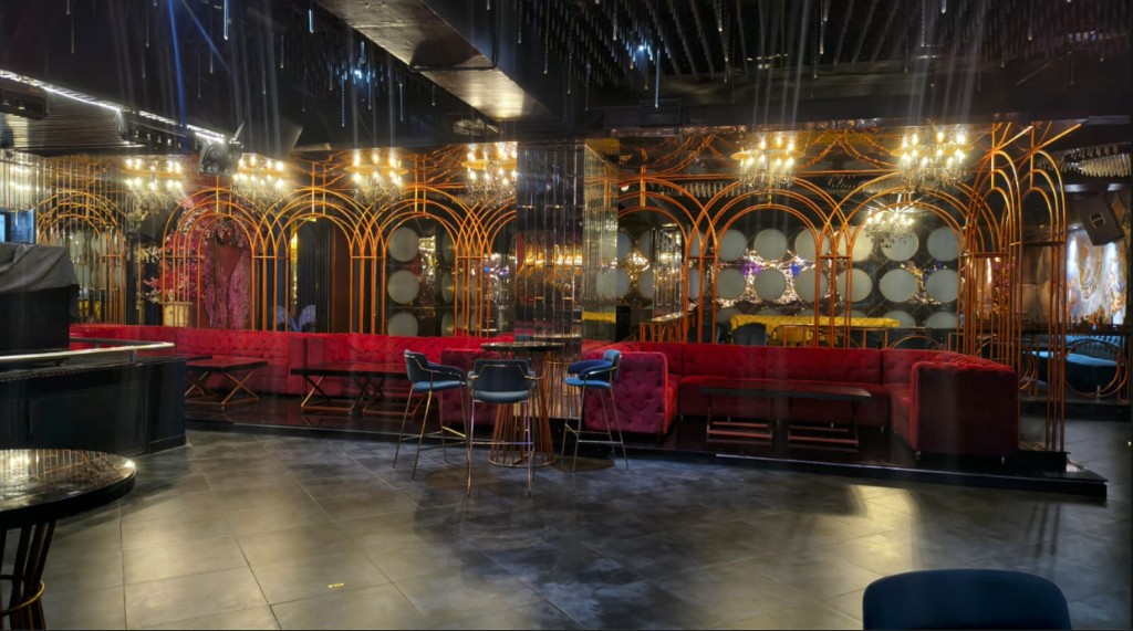 Red tufted banquettes framed by gold art-deco arches and chandeliers