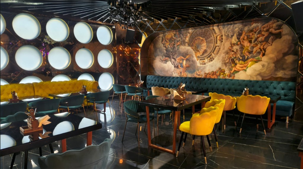 Dining room with a yellow tufted sofa, teal banquette, and a renaissance mural