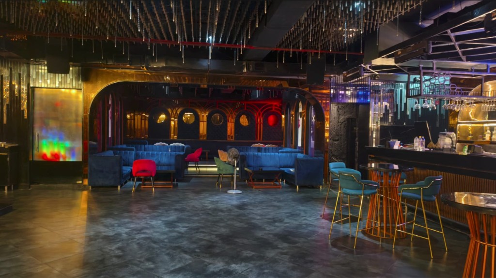 Blue velvet sofas in arched alcoves with red lighting and a bar along the side